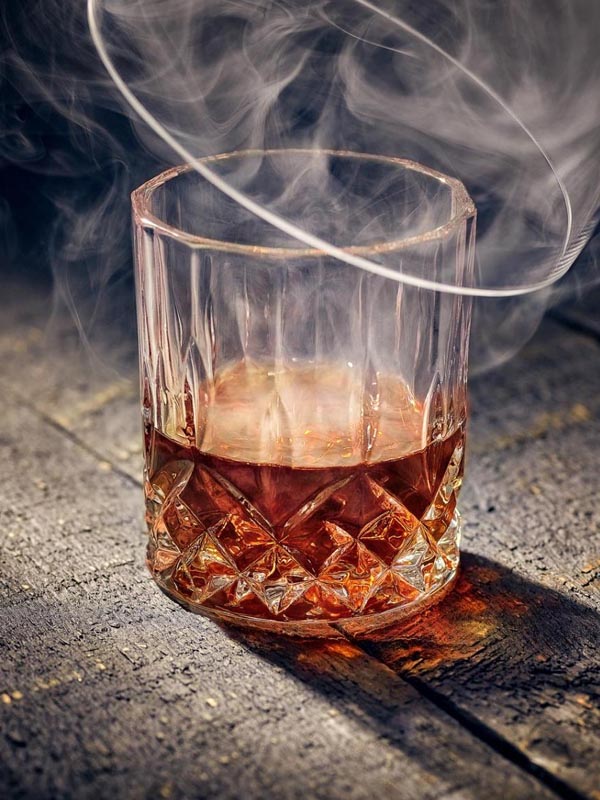A bourbon glass is covered in smoke