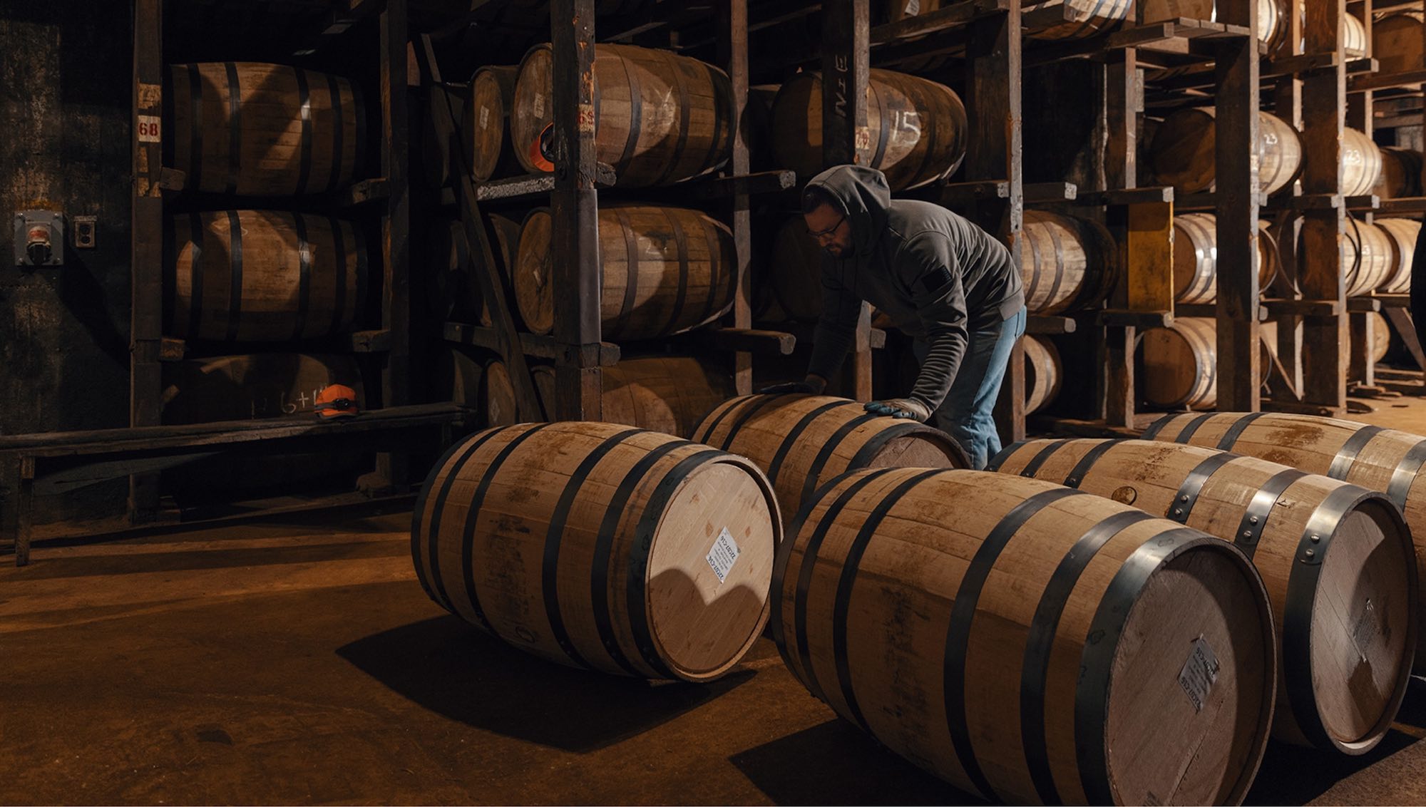 A man pushes barrels of bourbon through the distillery