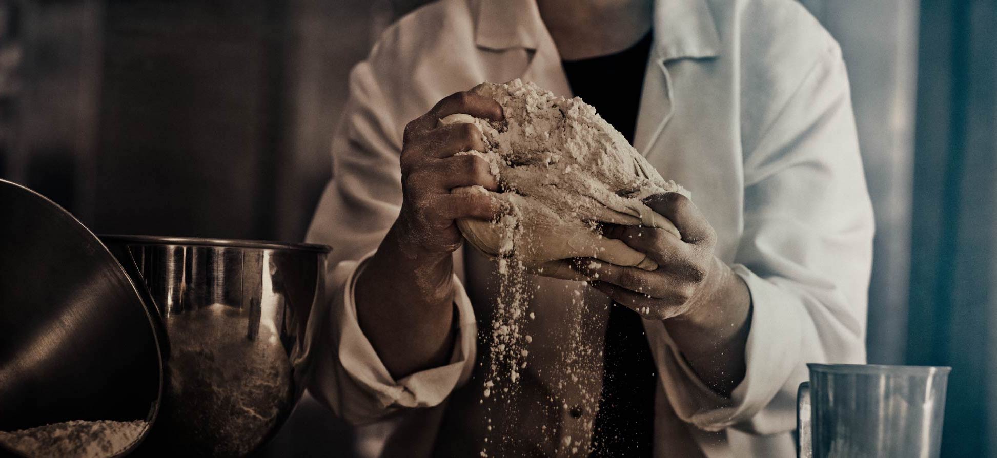 A food scientist kneads dough covered in flour